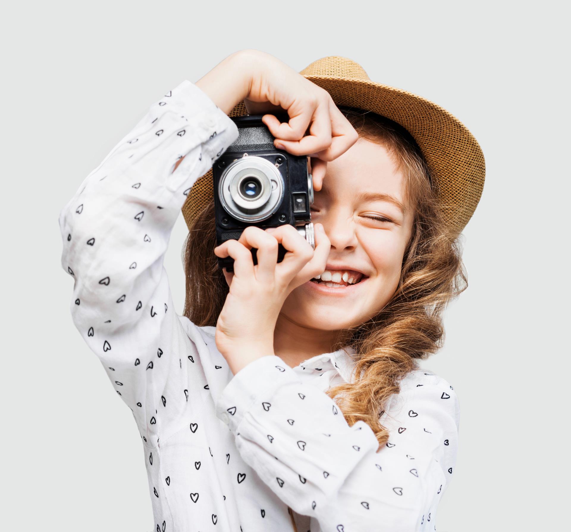 Girl in hat taking picture with old camera