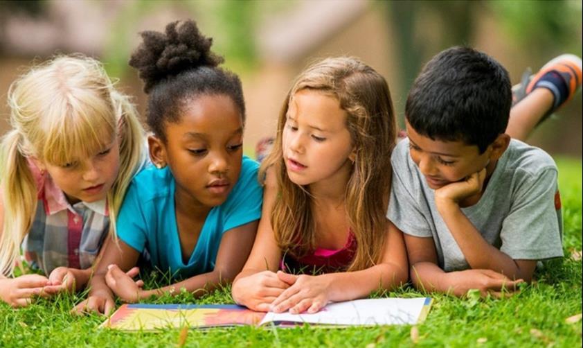 Children reading laying in the grass