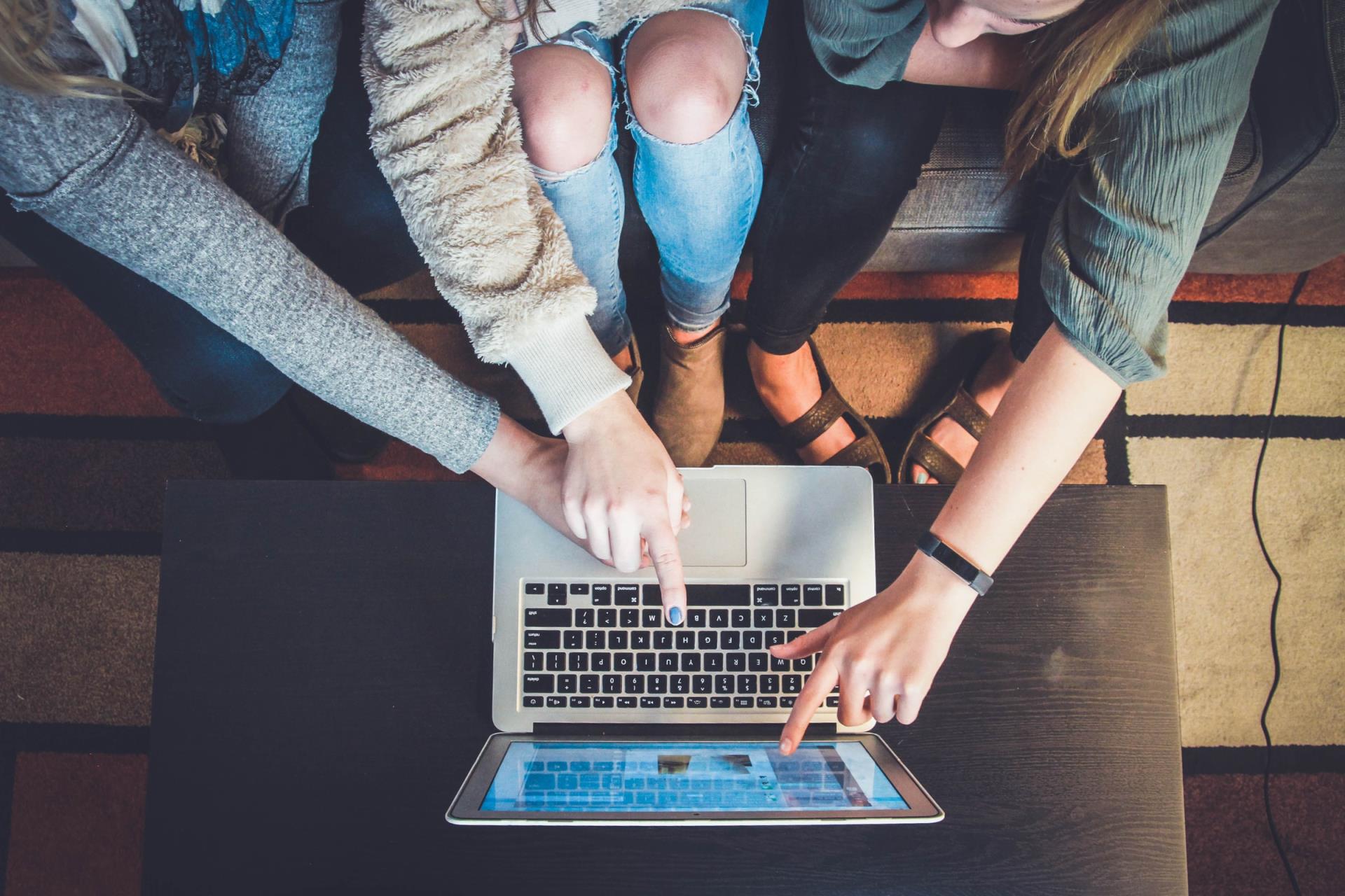 Group of people pointing at laptop screen