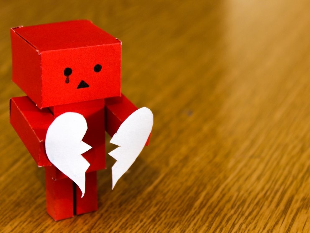 crying robot holding broken heart