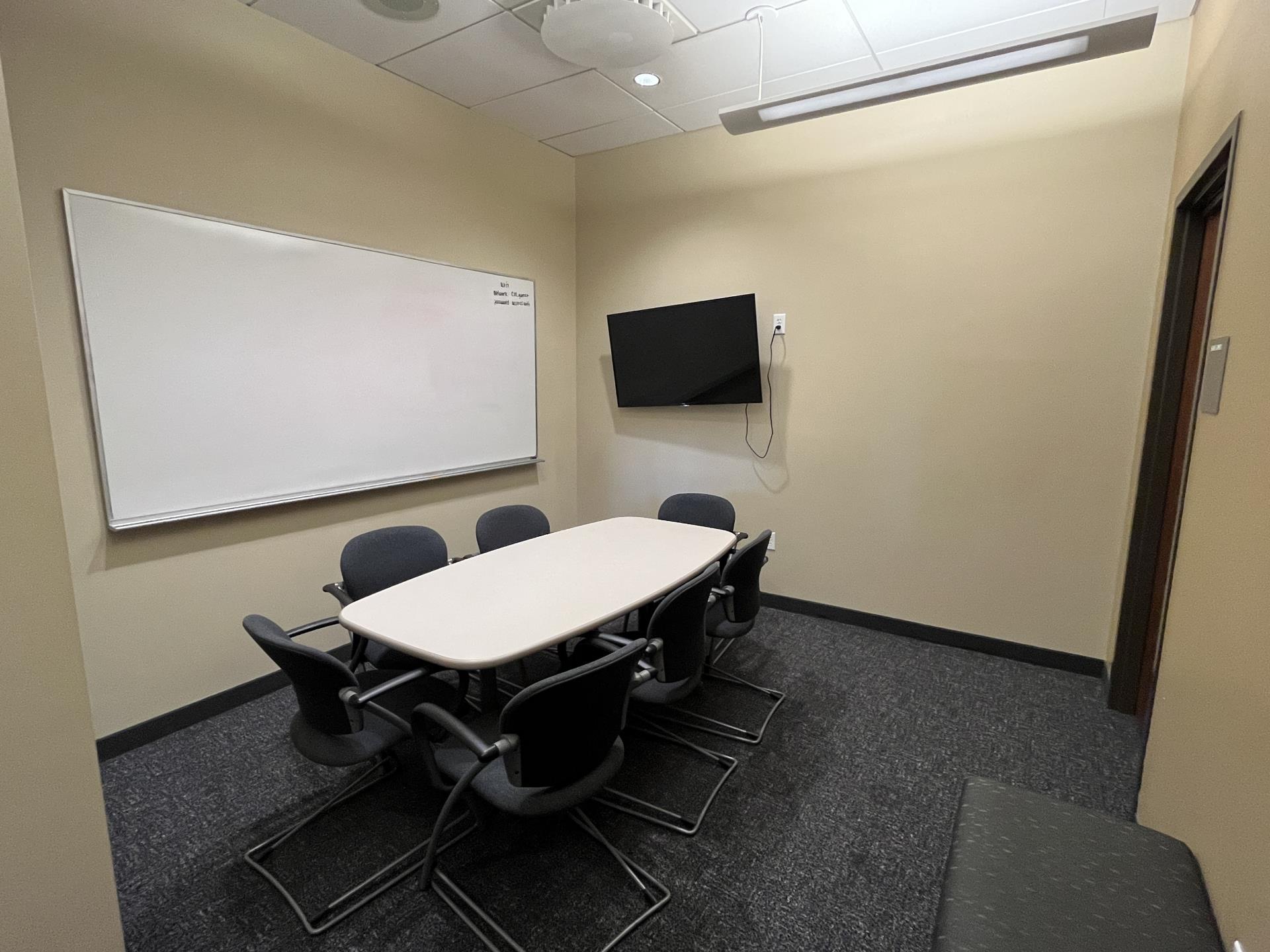 Long white table, TV, whiteboard, and chairs