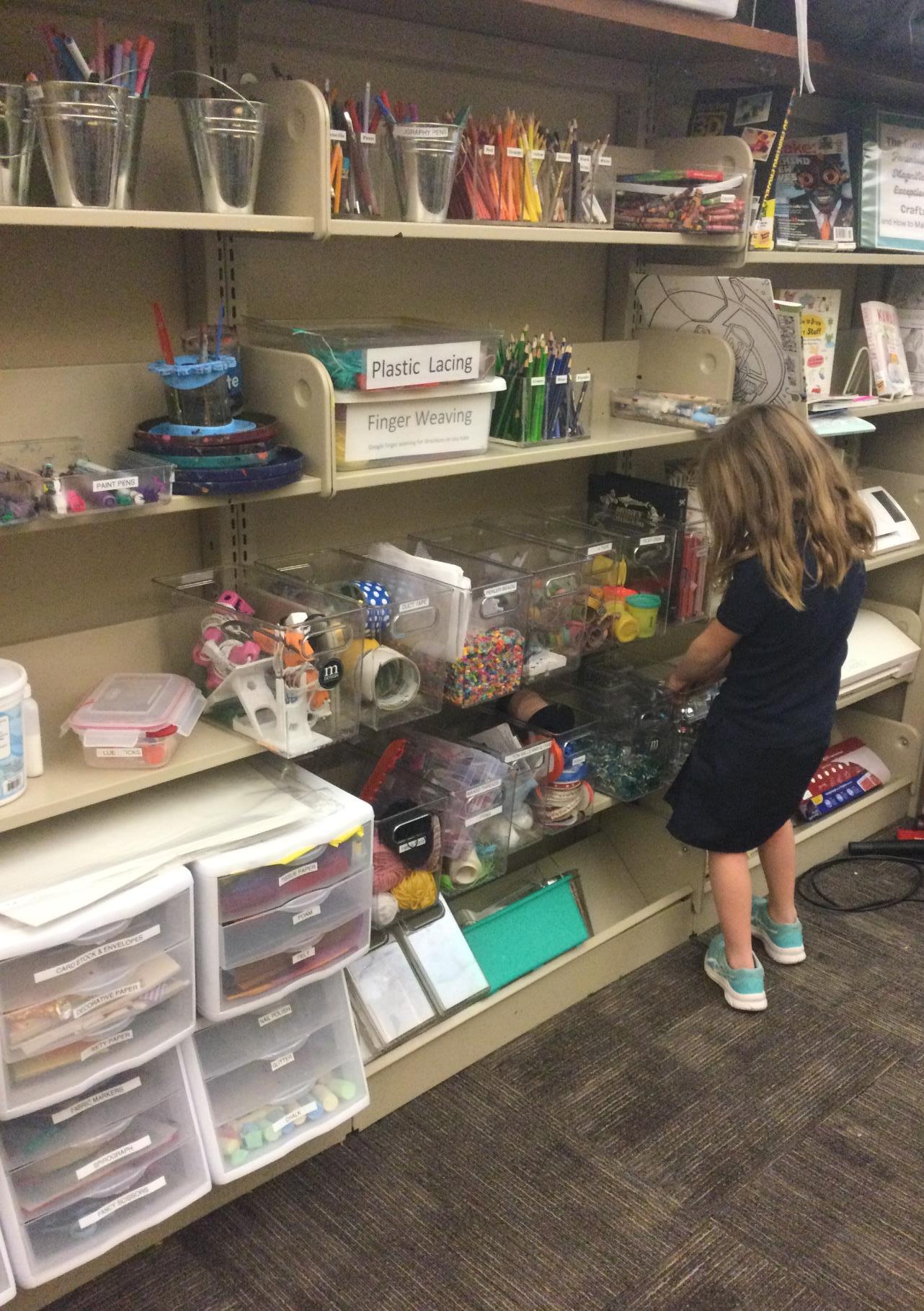 girl standing at maker shelves teens