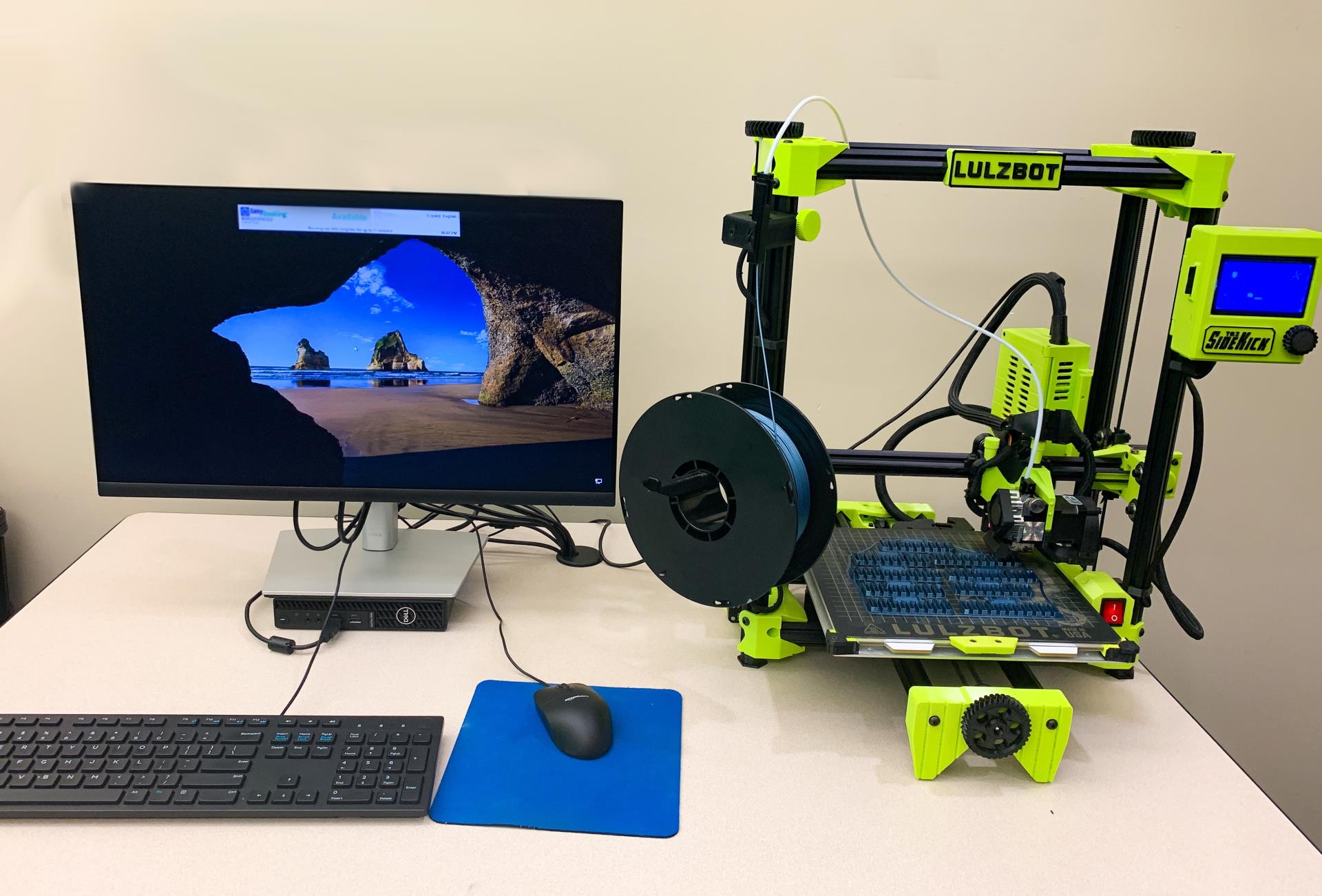 A windows computer with mouse and keyboard next to a  Lulzbot Brand Sidekick 3D printer